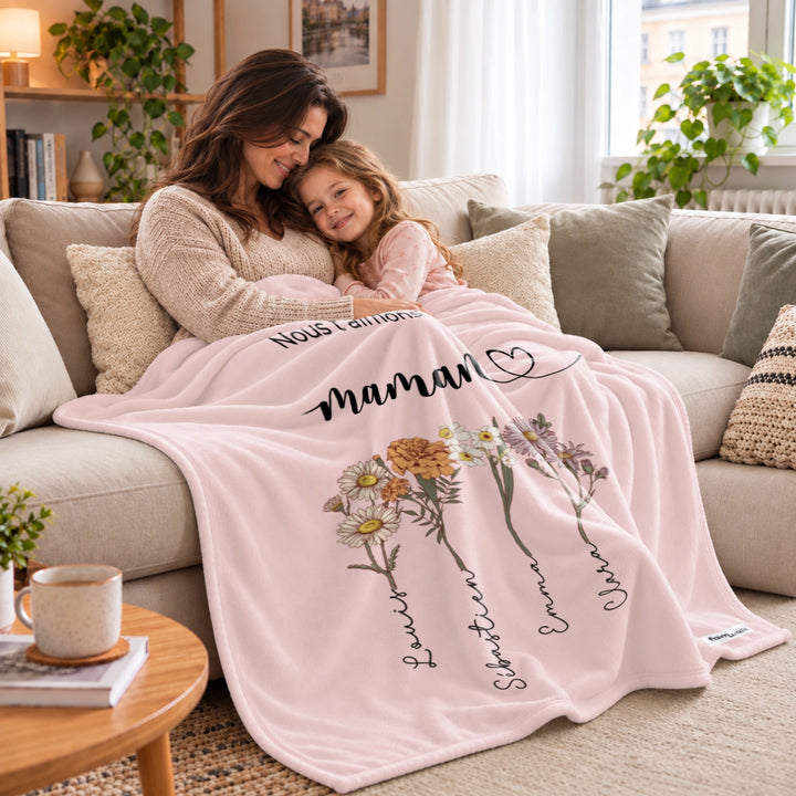 Mère et fille câlinées sous le plaid rose Des fleurs pour maman sur le canapé market_france