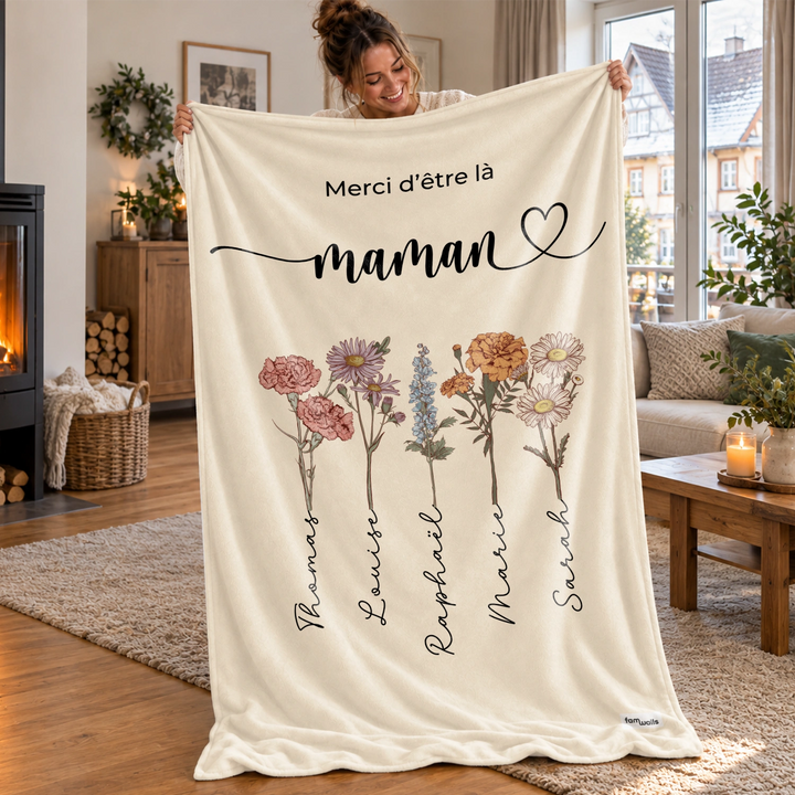 Femme tient le plaid Des fleurs pour maman avec cinq fleurs et prénoms près d'une cheminée market_france