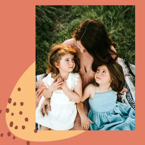 Eine Mutter kuschelt mit ihren zwei Töchtern auf einer Wiese - Symbolbild für die familiäre Geborgenheit, die famwalls mit personalisierten Geschenken feiert